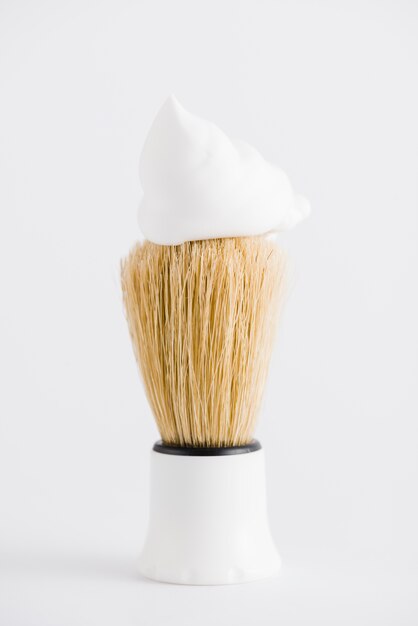 Espuma sobre la brocha de afeitar sintética sobre fondo blanco.