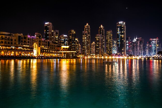 Espumosos Dubai rascacielos reflejan en el agua por la noche