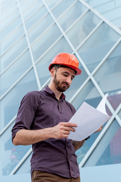 Foto gratuita esquema de lectura de trabajador con casco naranja