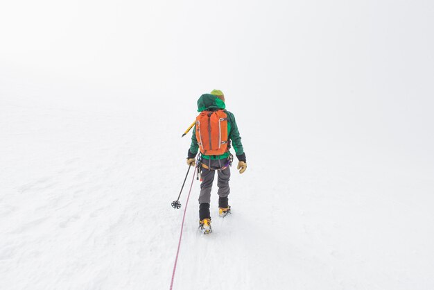Esquiador caminando por una empinada ladera nevada en las montañas