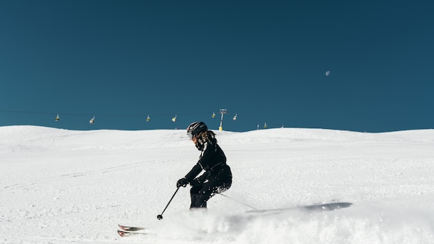 Esquiador esquiando en una superficie nevada con traje de esquí y casco