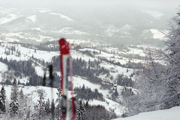 Esquís rojos y blancos puestos en la nieve con una gran vista de montaña detrás de ellos