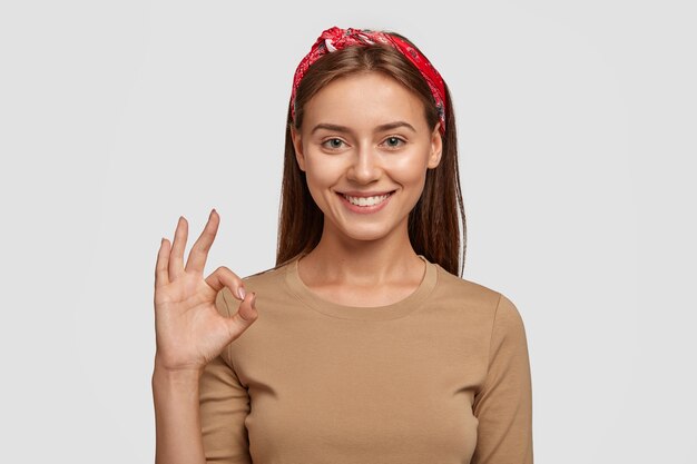 Está bien, no hay problema. Hermosa mujer sonriente muestra un gesto excelente, asegura un buen trabajo