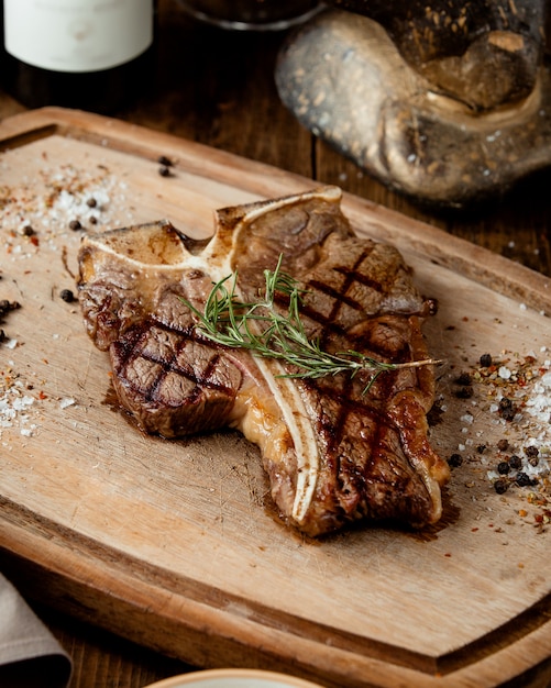 Estaca de t-bone a la parrilla adornada con hierbas y sal