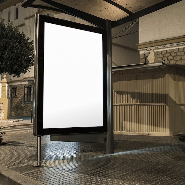 Estación de autobuses con pancarta en blanco iluminado en una calle
