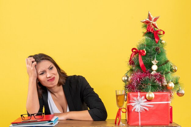 Estado de ánimo de año nuevo con hermosa dama de negocios seria confundida por algo y sentada en una mesa en la oficina