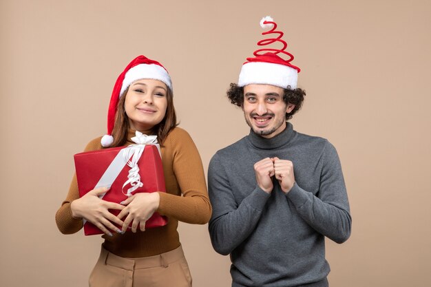 Estado de ánimo de año nuevo con una pareja encantadora divertida con sombreros rojos de santa claus en gris