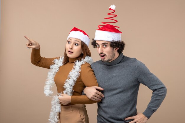 Estado de ánimo de año nuevo con una pareja encantadora satisfecha fresca emocionada con sombreros rojos de santa claus disfrutando