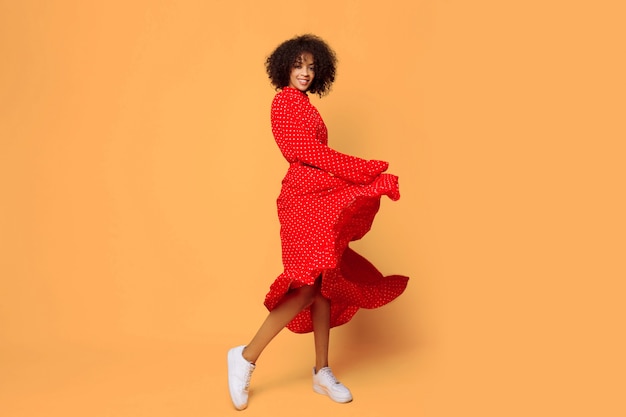 Estado de ánimo de ensueño. Chica africana con estilo bailando y saltando en naranja