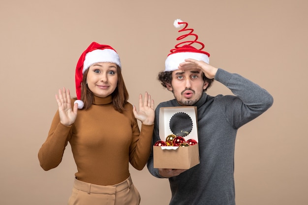 Estado de ánimo festivo, con, emocionado, fresco, pareja, llevando, rojo, santa claus, sombreros, en, gris colección de imágen