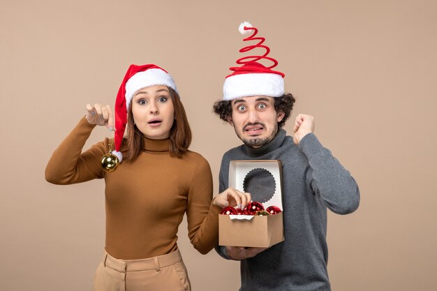 Estado de ánimo festivo con pareja fresca encantadora emocionada con sombreros rojos de santa claus en imágenes grises