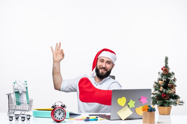 Estado de ánimo de Navidad con un adulto joven positivo con gorro de Papá Noel y usar un calcetín de Navidad en la mano mostrando tres en la oficina