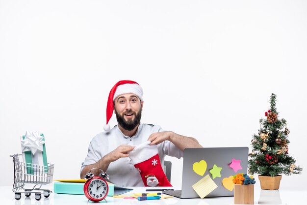 Estado de ánimo de Navidad con adultos jóvenes con gorro de Papá Noel y mirando dentro del calcetín de Navidad felizmente en la oficina