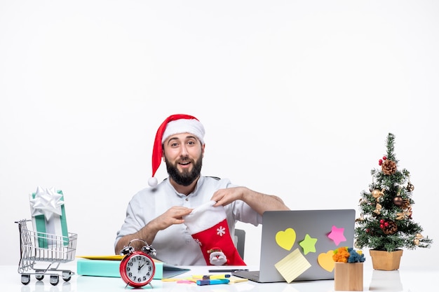 Estado de ánimo de Navidad con adultos jóvenes con gorro de Papá Noel y mirando dentro del calcetín de Navidad felizmente en la oficina