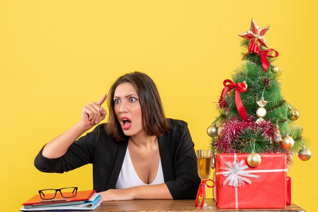 Estado de ánimo de Navidad con la joven dama de negocios emocional enojada tensa nerviosa apuntando hacia atrás en amarillo