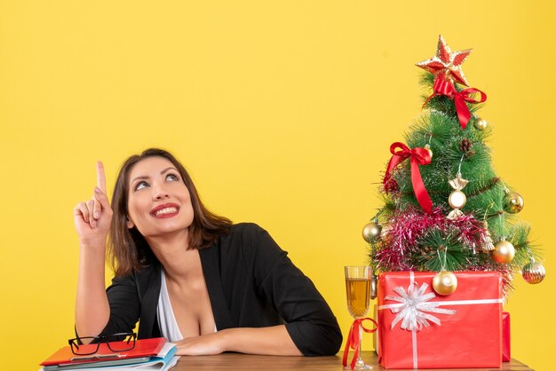 Estado de ánimo de Navidad con joven empresaria apuntando hacia arriba