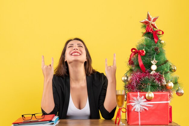 Estado de ánimo de Navidad con joven empresaria feliz disfrutando de su éxito y sentada en la oficina