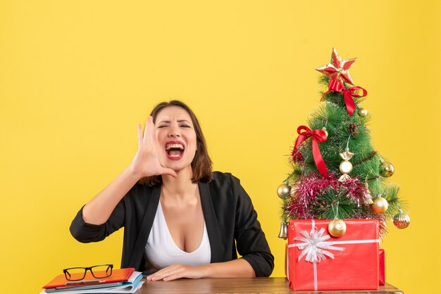 Estado de ánimo de Navidad con mujer hermosa joven llamando a algo mirando hacia adelante en la oficina