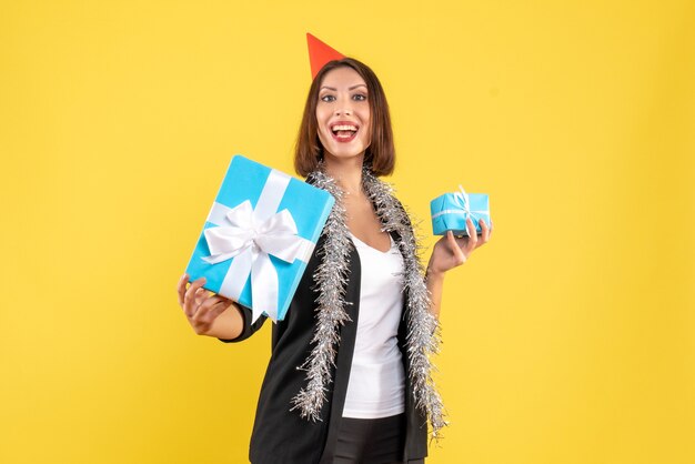 Estado de ánimo navideño con orgullosa dama de negocios en traje con sombrero de Navidad mostrando su regalo en amarillo