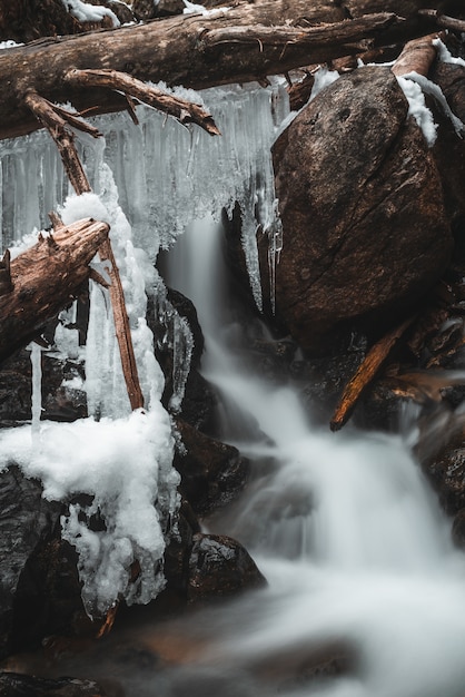 Estalactitas de hielo sobre troncos en una cascada.