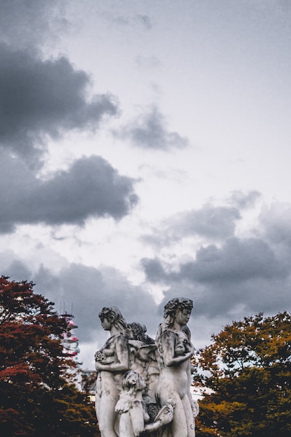 Estatua de hormigón femenino bajo nubes blancas