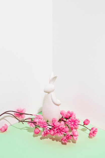 Estatuilla de conejo blanco con flores en la mesa