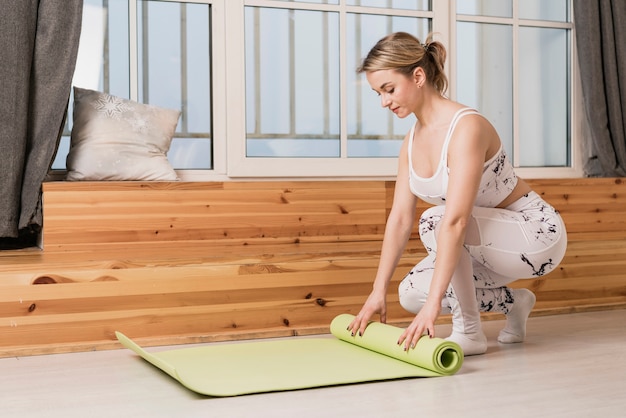 Estera de yoga rodante de mujer de alto ángulo