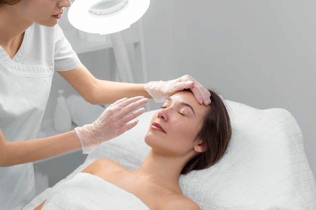 Esteticista con clienta en el salón de rutina de cuidado facial