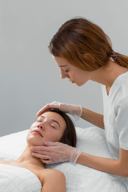 Esteticista con clienta en el salón de rutina de cuidado facial