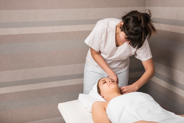 Esteticista envolviendo una toalla en la cabeza de una mujer joven relajada en el spa