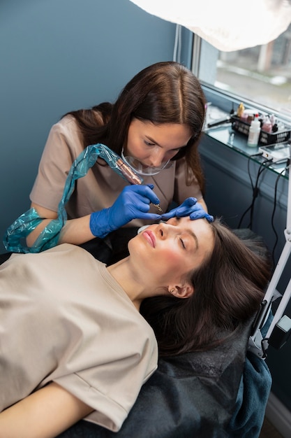 Esteticista haciendo un tratamiento de cejas para su clienta