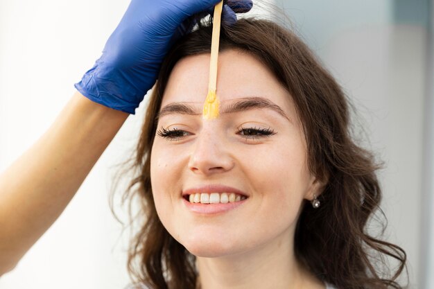 Esteticista haciendo un tratamiento de cejas para su clienta