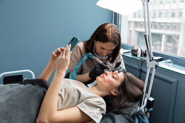 Esteticista haciendo un tratamiento de cejas para su cliente.