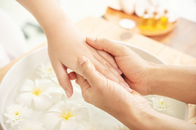 Esteticista masajeando la mano del cliente de salón spa femenino. Tratamiento de spa y producto para pies femeninos y spa de manos.