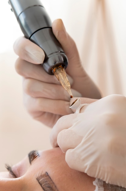 Esteticista realizando un procedimiento de microblading en las cejas de un cliente.