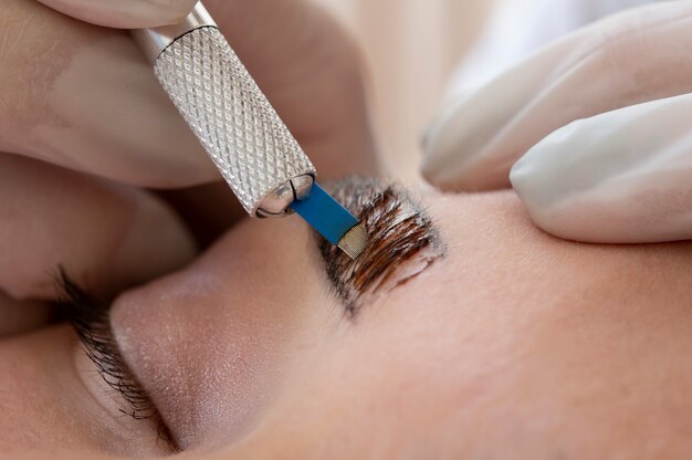 Esteticista realizando un procedimiento de microblading en las cejas de un cliente.