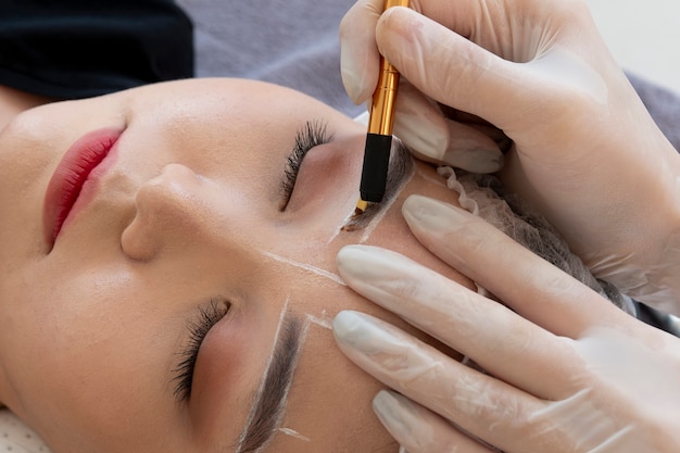 Esteticista realizando un procedimiento de microblading en las cejas de un cliente.