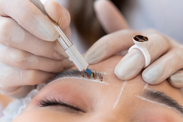 Esteticista realizando un procedimiento de microblading en las cejas de un cliente.