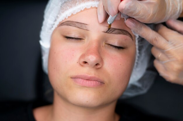 Esteticista realizando un procedimiento de microblading en una mujer en un salón de belleza