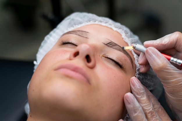 Esteticista realizando un procedimiento de microblading en una mujer en un salón de belleza