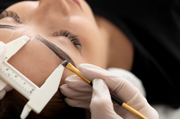 Esteticista trabajando en las cejas de un cliente.