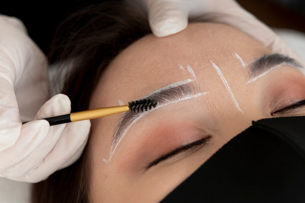 Esteticista trabajando en las cejas de un cliente.