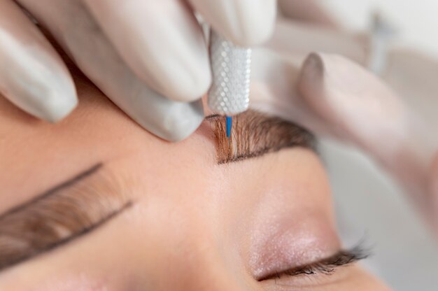 Esteticista trabajando en las cejas de un cliente.