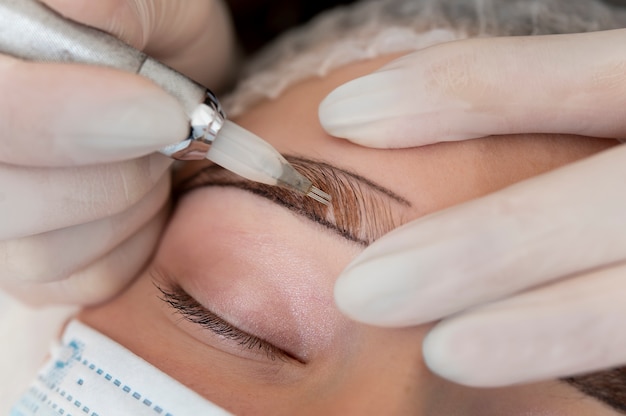 Foto gratuita esteticista trabajando en las cejas de un cliente.