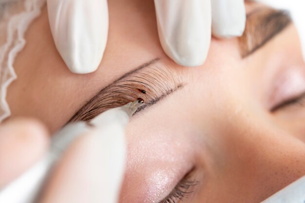 Esteticista trabajando en las cejas de un cliente.