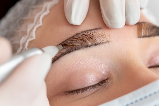 Esteticista trabajando en las cejas de un cliente.