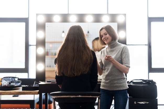 Estilista alegre aplicar maquillaje en mujer anónima