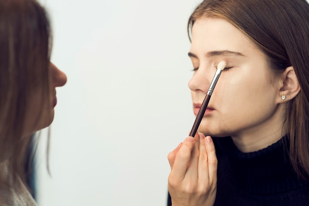 Estilista aplicando sombra de ojos en hermosa modelo