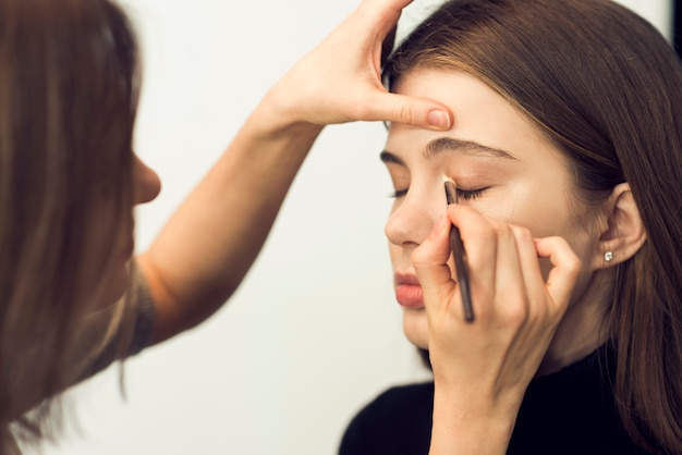 Estilista aplicando sombra de ojos en modelo