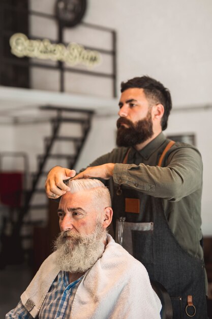 Estilista de cabello corrigiendo peinado a cliente hombre.